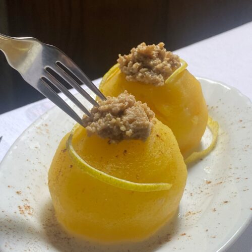 two stuffed apples, a fork and white plate