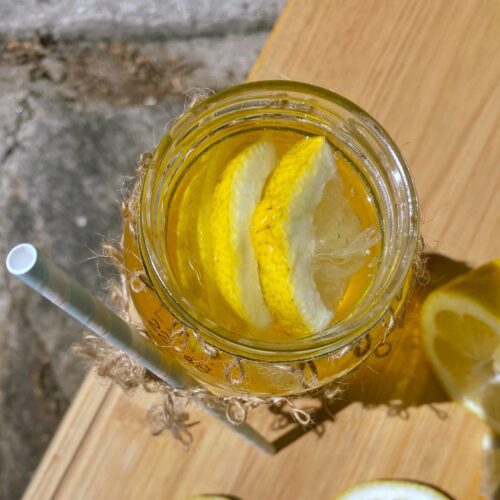 rooibos tea with lemon slices in a jar, on a wooden board