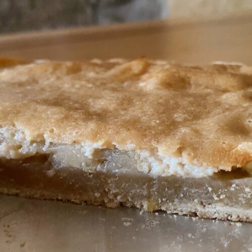 vegan apple and cheese tart on a silver plate on a wooden table