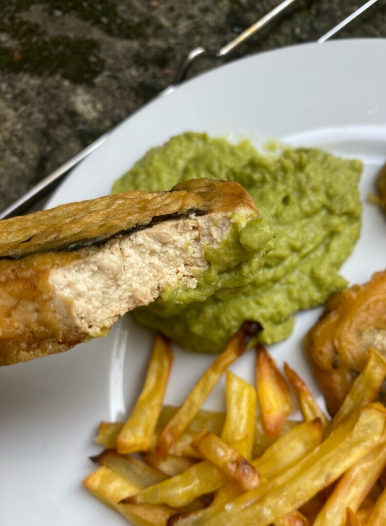 tofish bitten off and pea mash on a white plate